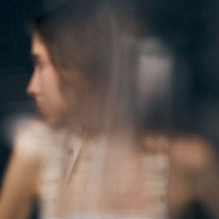 A soft, out-of-focus portrait of a woman seen through glass, conveying mystery and contemplative mood. Ideal for themes of privacy, distance, and emotional depth in visual storytelling.