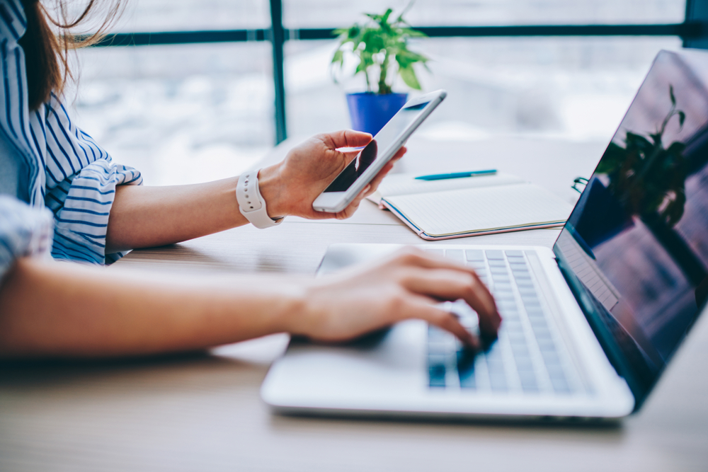 Frau mit Smartphone und Laptop