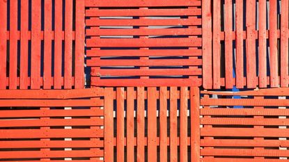 Orange shipping pallets stacked as a fence