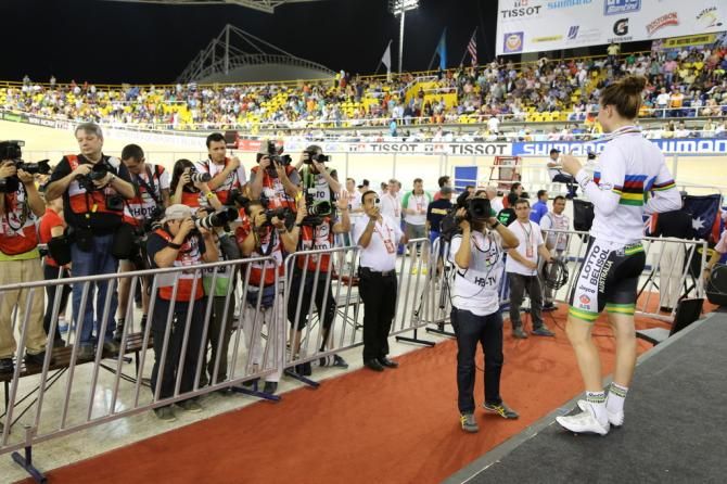 Amy Cure poses for the photographers with her rainbow jersey and gold medal