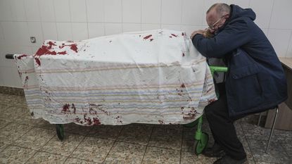 A man named Serhii cries over the lifeless body of his teenage son, Iliya, in Mariupol, Ukraine.