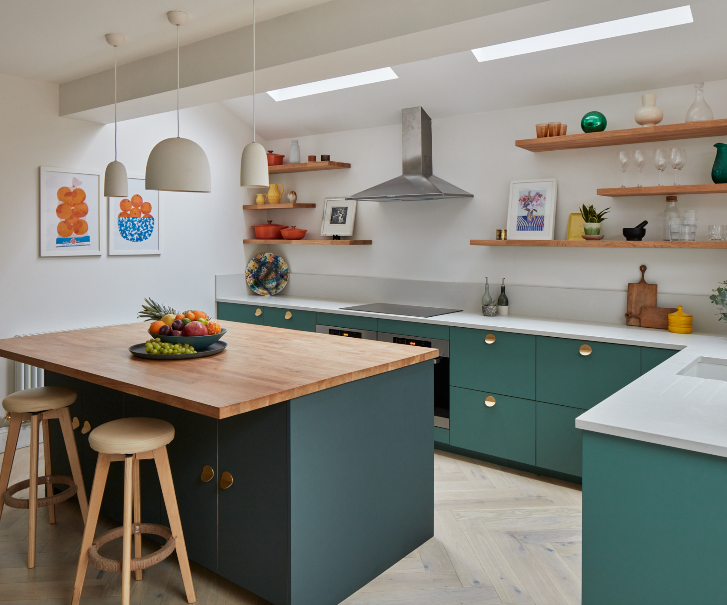 kitchen with green cabinets and kitchen island with wooden worktop and three white concrete style pendant lights in different sizes above island