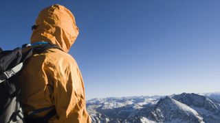 hard shell vs soft shell: person in waterproof looking across mountains