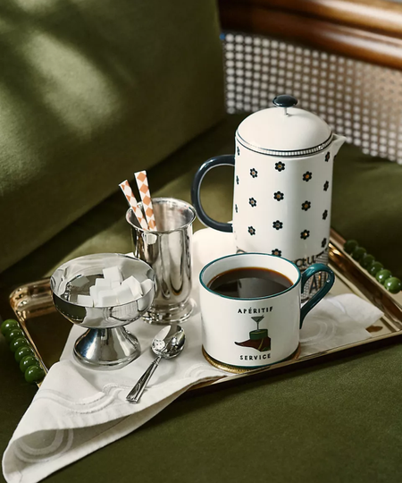 a serving tray with a coffee cup a french press, and silver cups