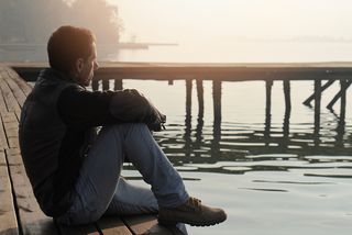 A man sits alone on a dock