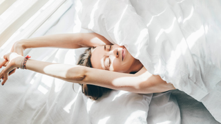 Woman stretching in bed after waking up