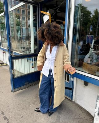 Influencer wears a country coat, a white blouse, blue baggy jeans, and black pointed toe heels.