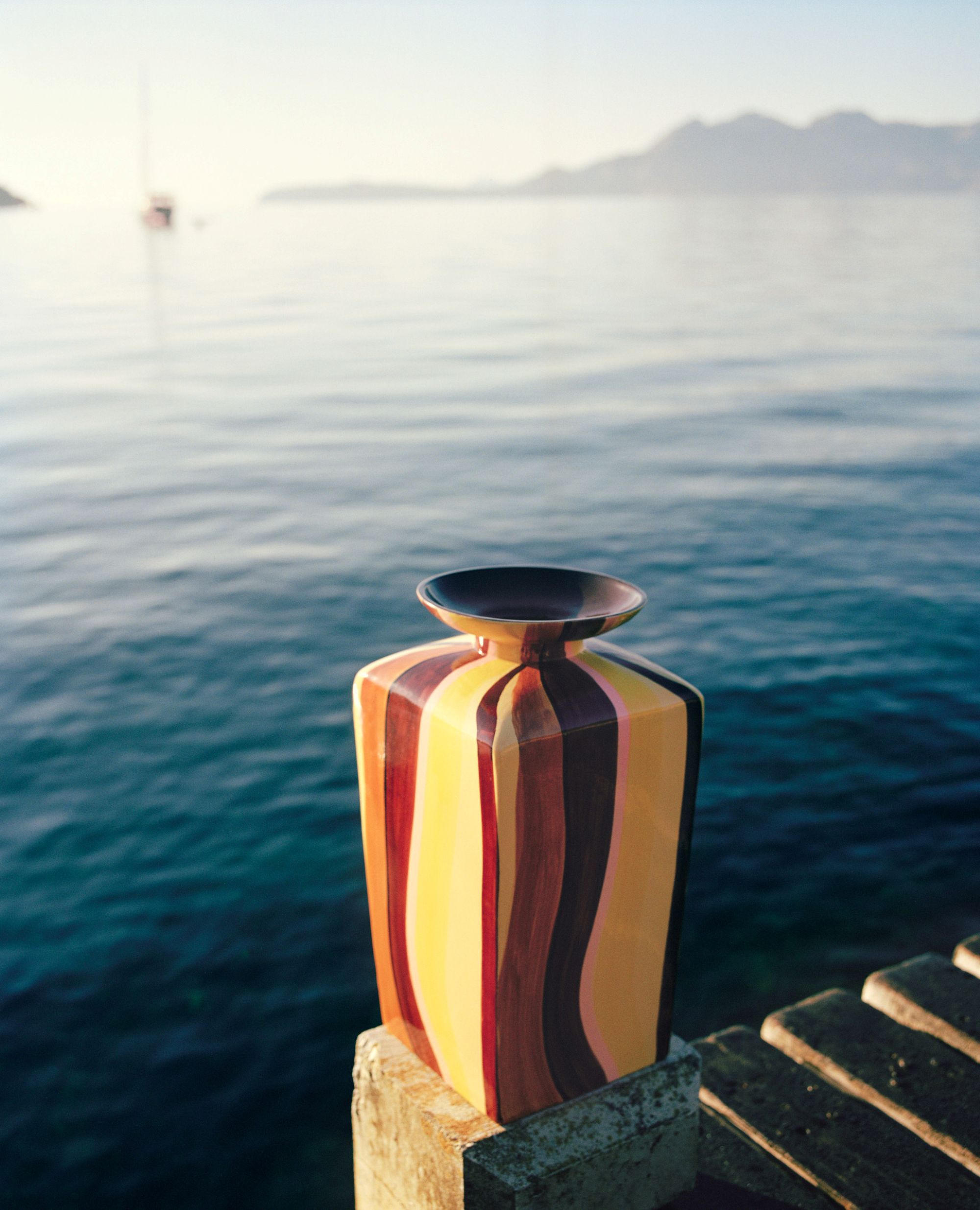 a colorful vase in front of a body of water