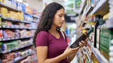 Woman looking at a bottle of oil in a grocery store aisle