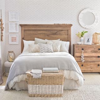 White rustic bedroom with smart wood bedhead, wooden chest of drawers and natural rug