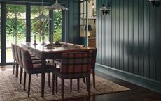 A dining toom with darkblue walls and dark wood flooring