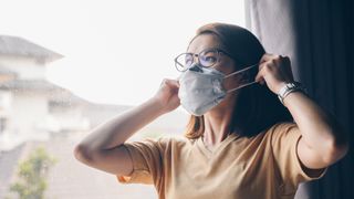 Air purifiers vs humidifers: what's the difference? Image of woman putting on face mask