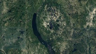 a large circular depression seen on a satellite photo of a green area on earth