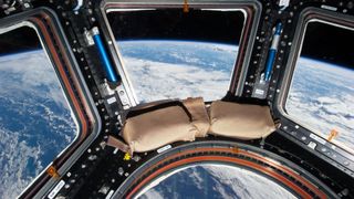 a view of clouds above the blue oceans of earth as seen through the windows of a space station