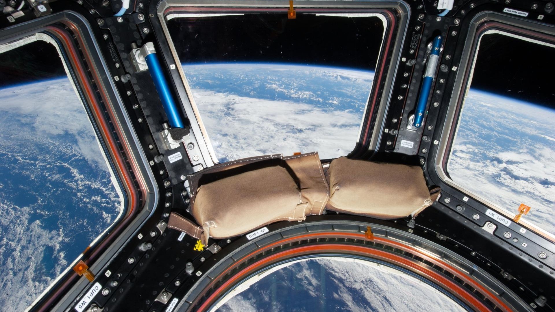 a view of clouds above the blue oceans of earth as seen through the windows of a space station