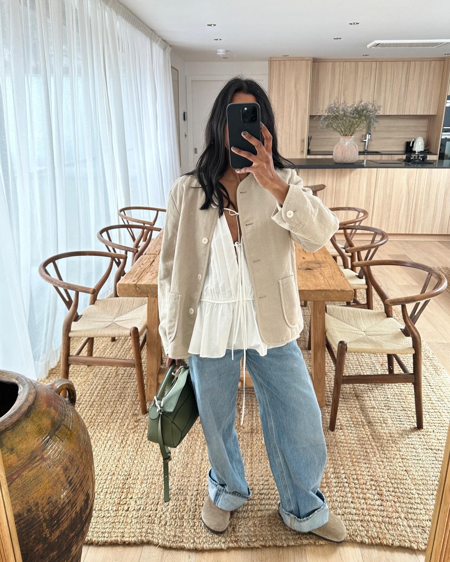 Influencer wears a white tie-front top from Tove underneath a suede jacket with blue jeans and Birkenstock mules.