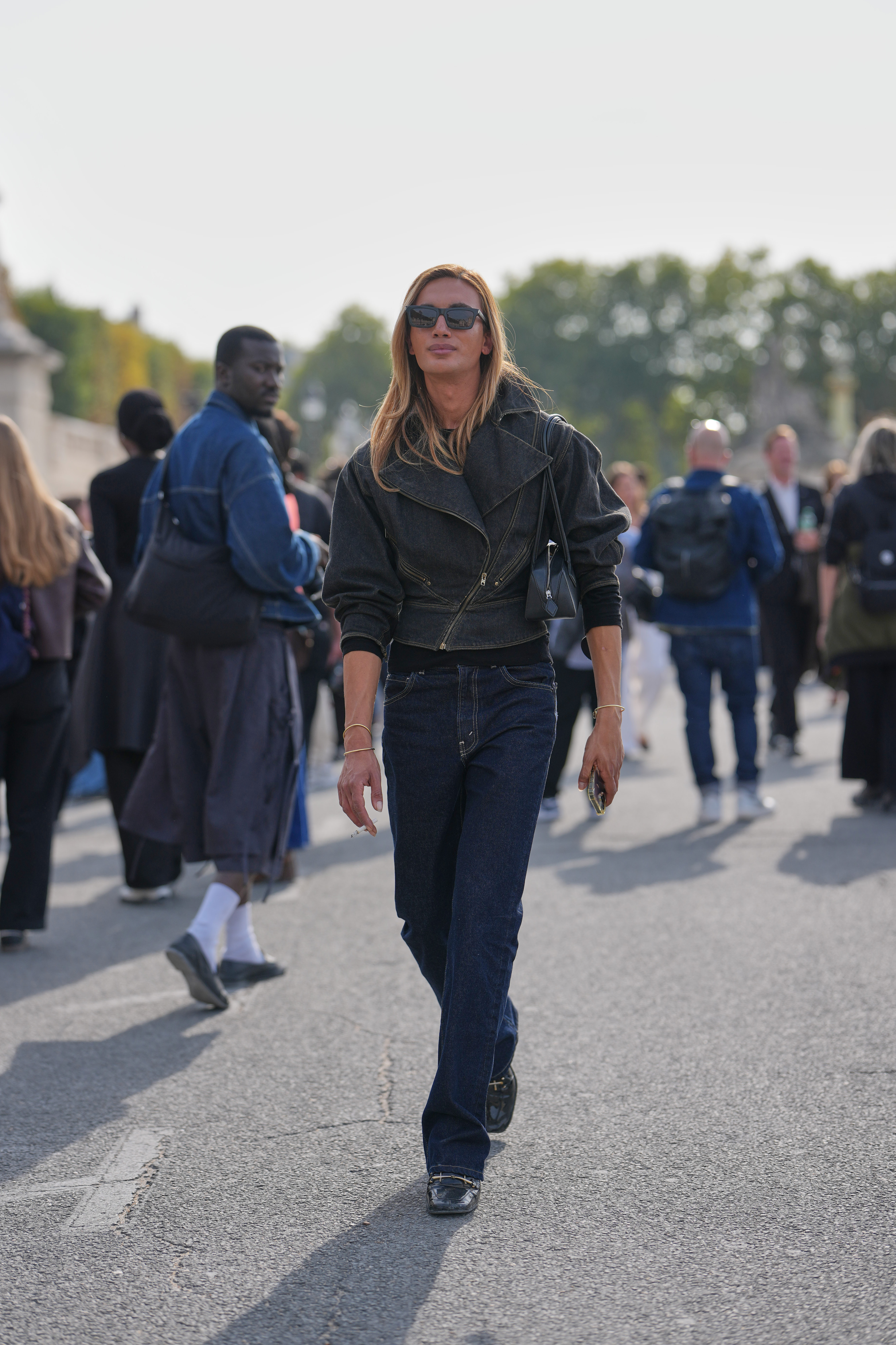 A guest wears long honey-blond straight hair with a center part, black rectangular sunglasses, dark indigo denim jeans