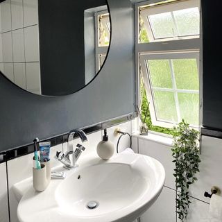 bathroom with round mirror and grey walls