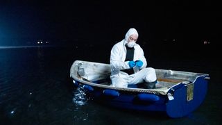 Tom Brannick (James Nesbitt) checks a phone in the boat in Bloodlands season 2