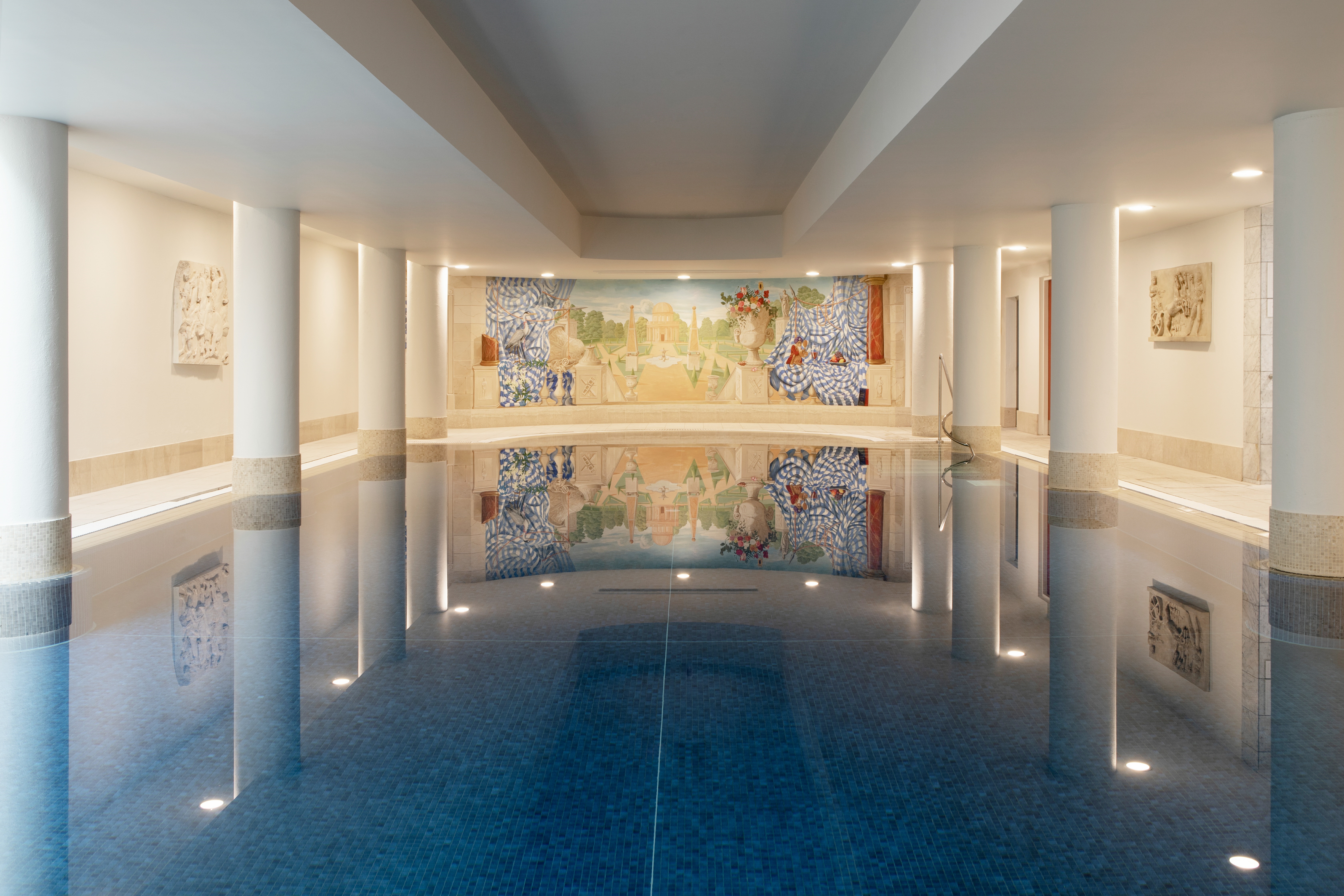 The pool at The Merrion hotel surrounded by white columns and a colorful mural