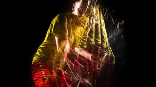 A stroboscopic flash portrait of a tennis player in a studio on a black background wearing a yellow shirt