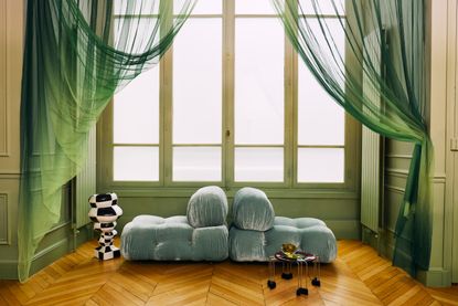A living room with green chairs and curtains