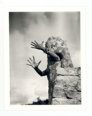 black and white photo of a woman's arms extending from rock structure
