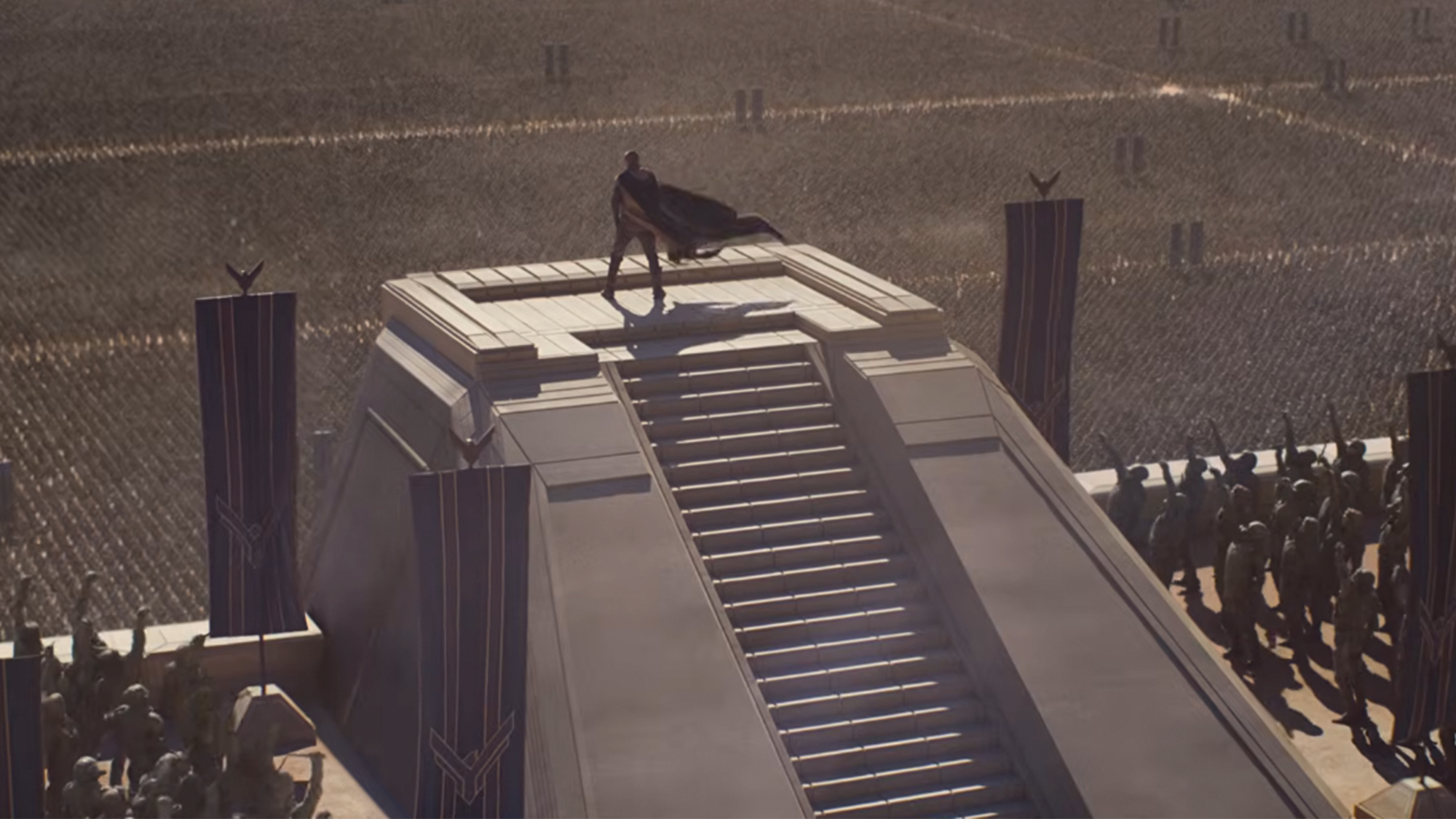 A person standing wearing a black cape standing atop a pyramid in Dune Part 3