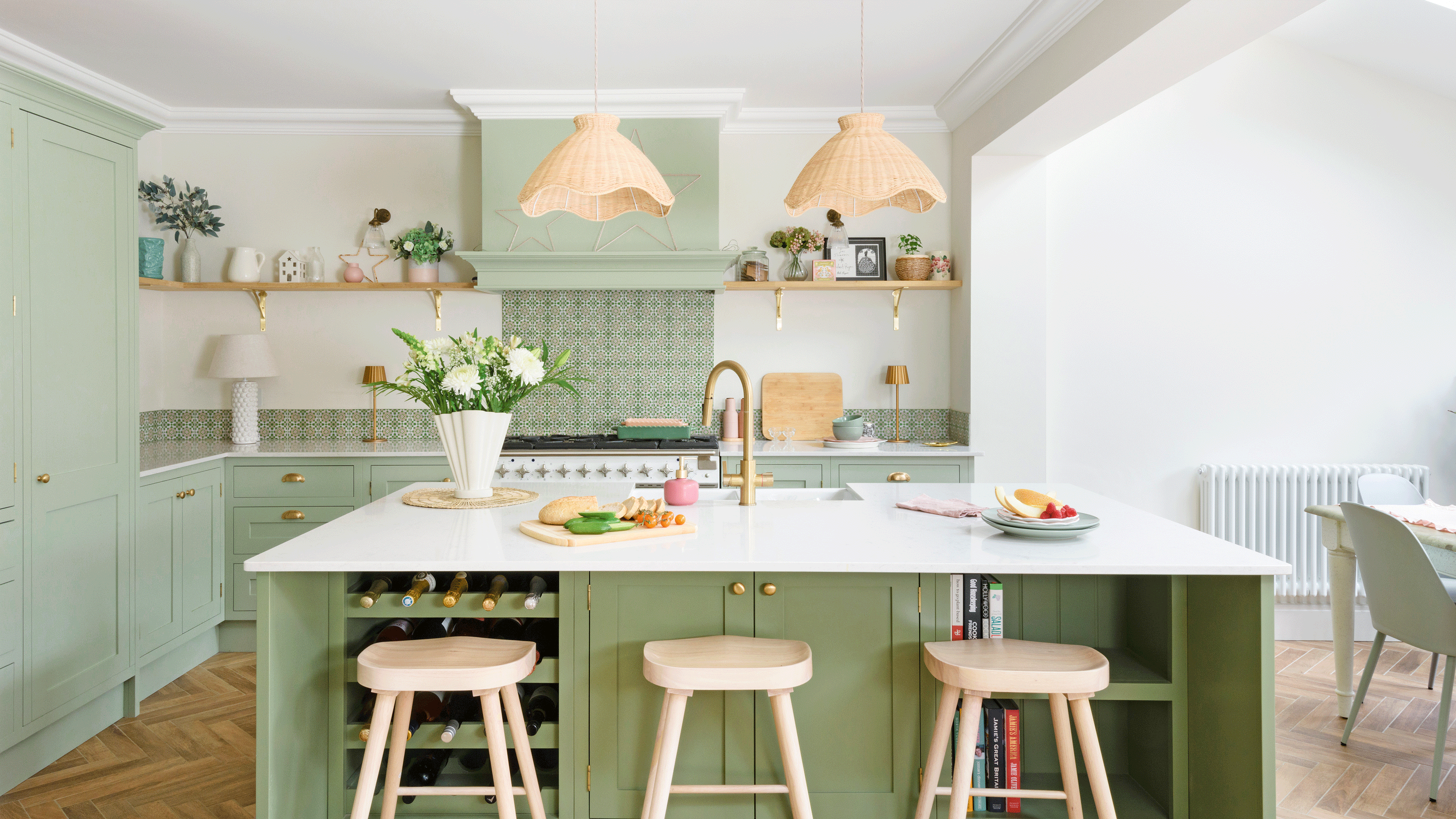 Green kitchen cabinets with white countertop and wooden stools