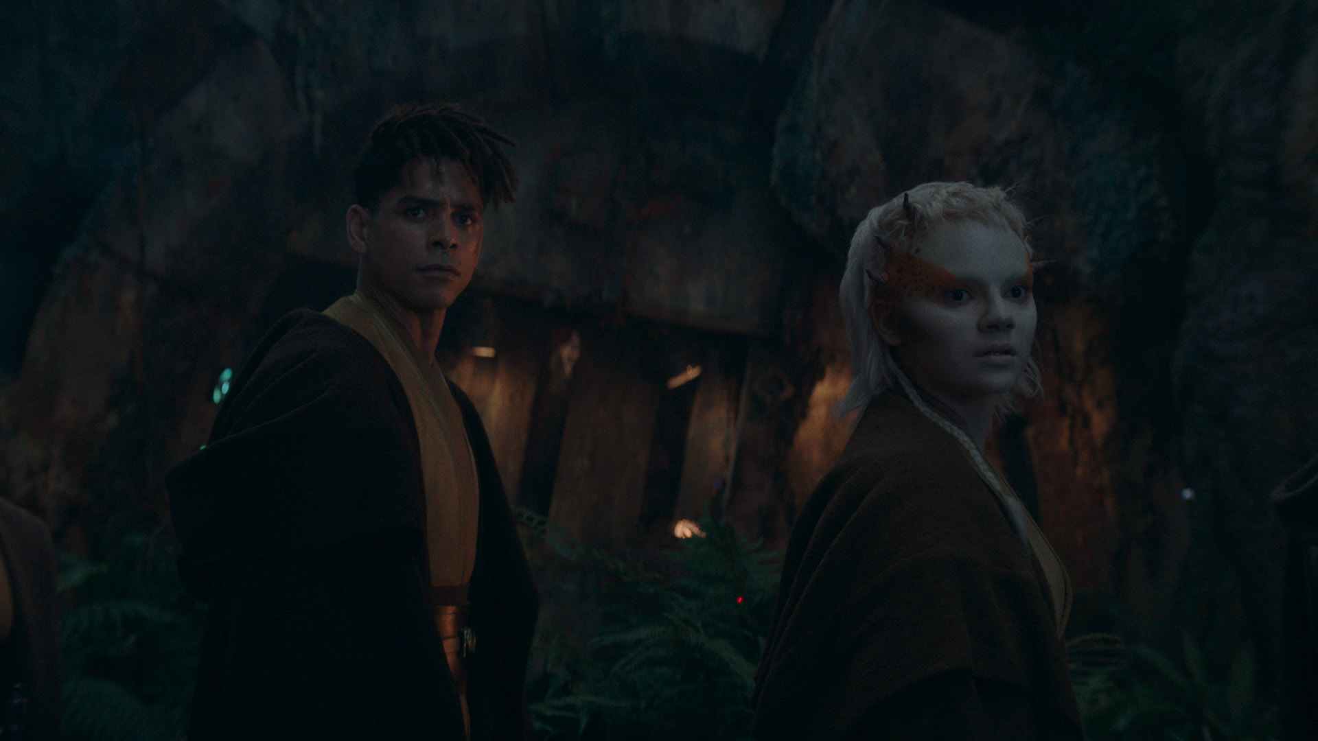 Yord et Jecki regardent quelque chose derrière eux dans une grotte dans Star Wars : The Acolyte.