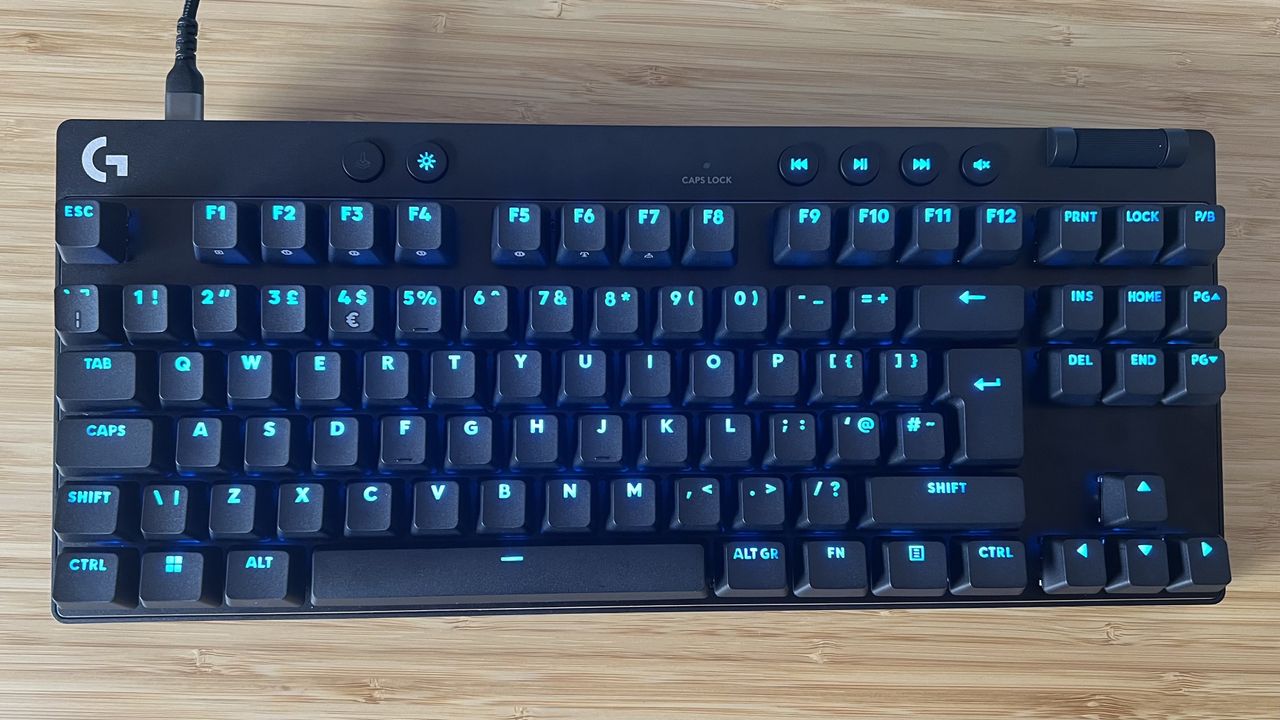 Logitech G Pro X TKL Rapid gaming keyboard on a wooden desk with blue lighting