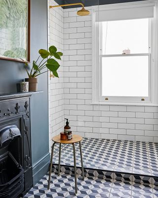 en suite shower room with geometric patterned floor tiles and dark blue walls shower with glass partition and white metro tiles