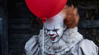 Bill Skarsgard as Pennywise holding red balloon in IT movie