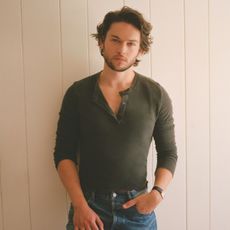 Actor Jack Martin shot by Max Montgomery for Who What Wear wearing an olive green three-quarter button-up shirt and jeans. 