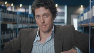 Hugh Grant leans on a bookshelf with a coy smile in Bridget Jones: The Edge of Reason.