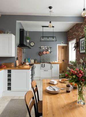 shaker style kitchen with grey walls, a wooden dining table, wooden worktops and industrial pendant lights