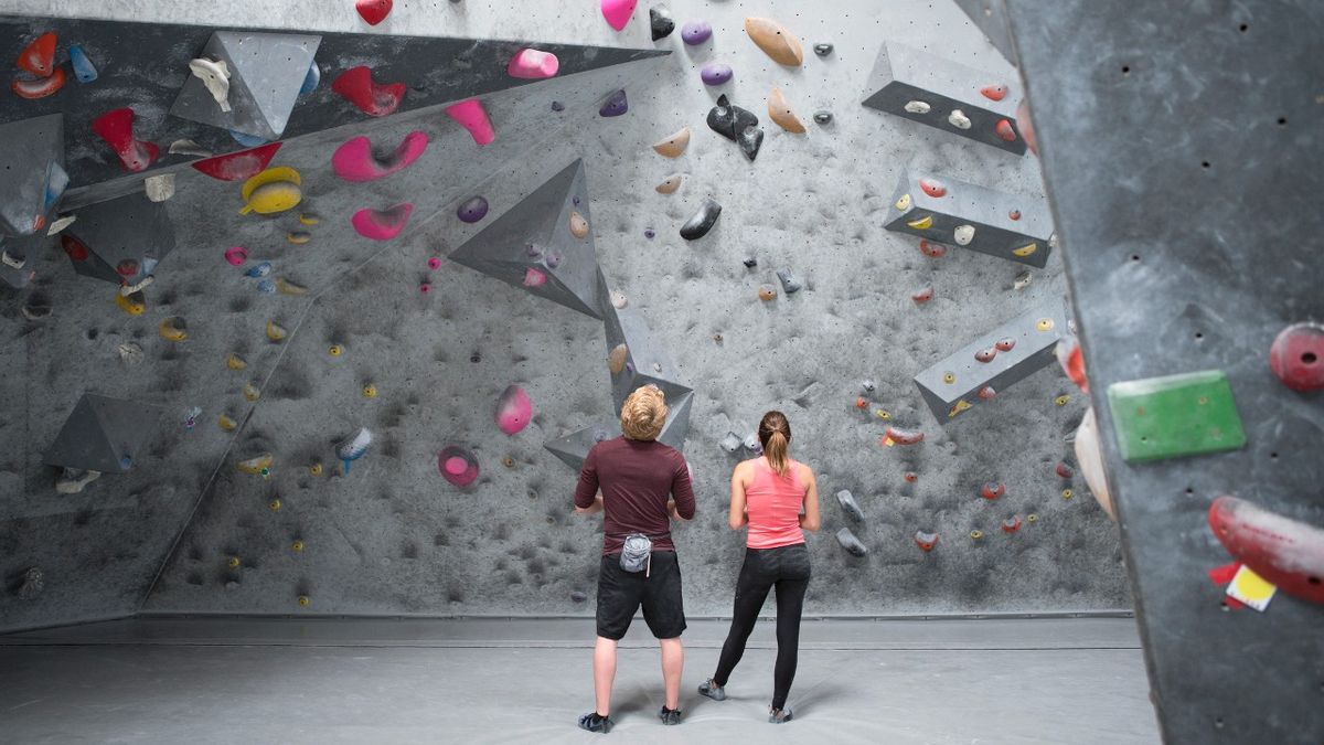 Two people look at a bouldering wall