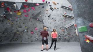 Two people look at a bouldering wall