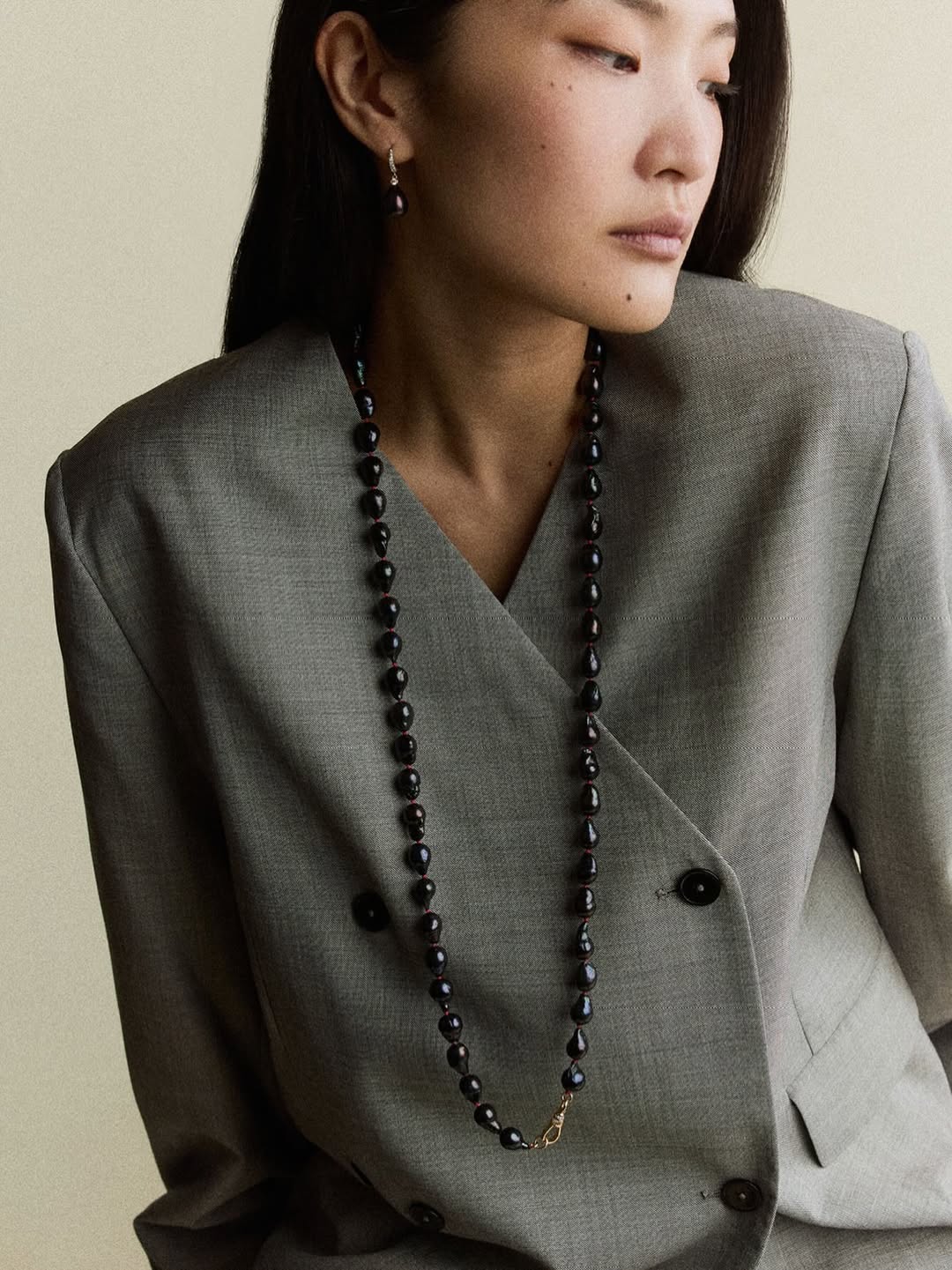 Lucy Delius model wears grey blazer black stone necklace