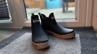 Barbour Mallow welly boots sat on a mat near a door