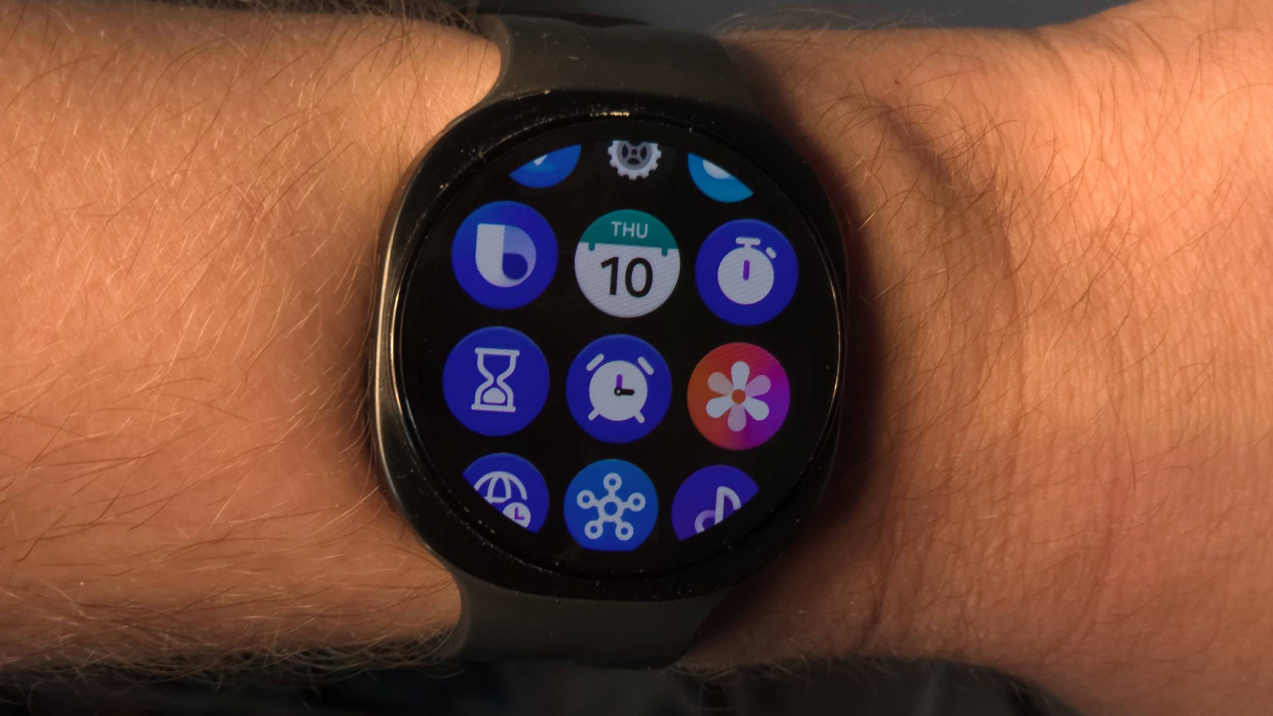 The Samsung Galaxy Watch 9 on a man's wrist, showing the app list.