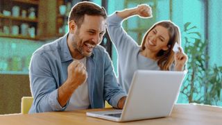 Young couple using a laptop and celebrating