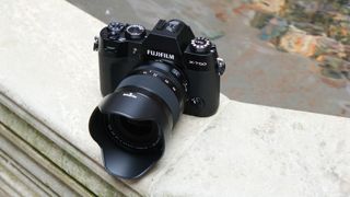 Fujifilm X-T50 camera on a stone wall in front of a pool of water