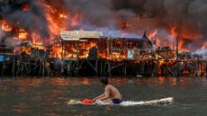 A man watches as fire rips through hundreds of houses in a coastal shanty town in Manila