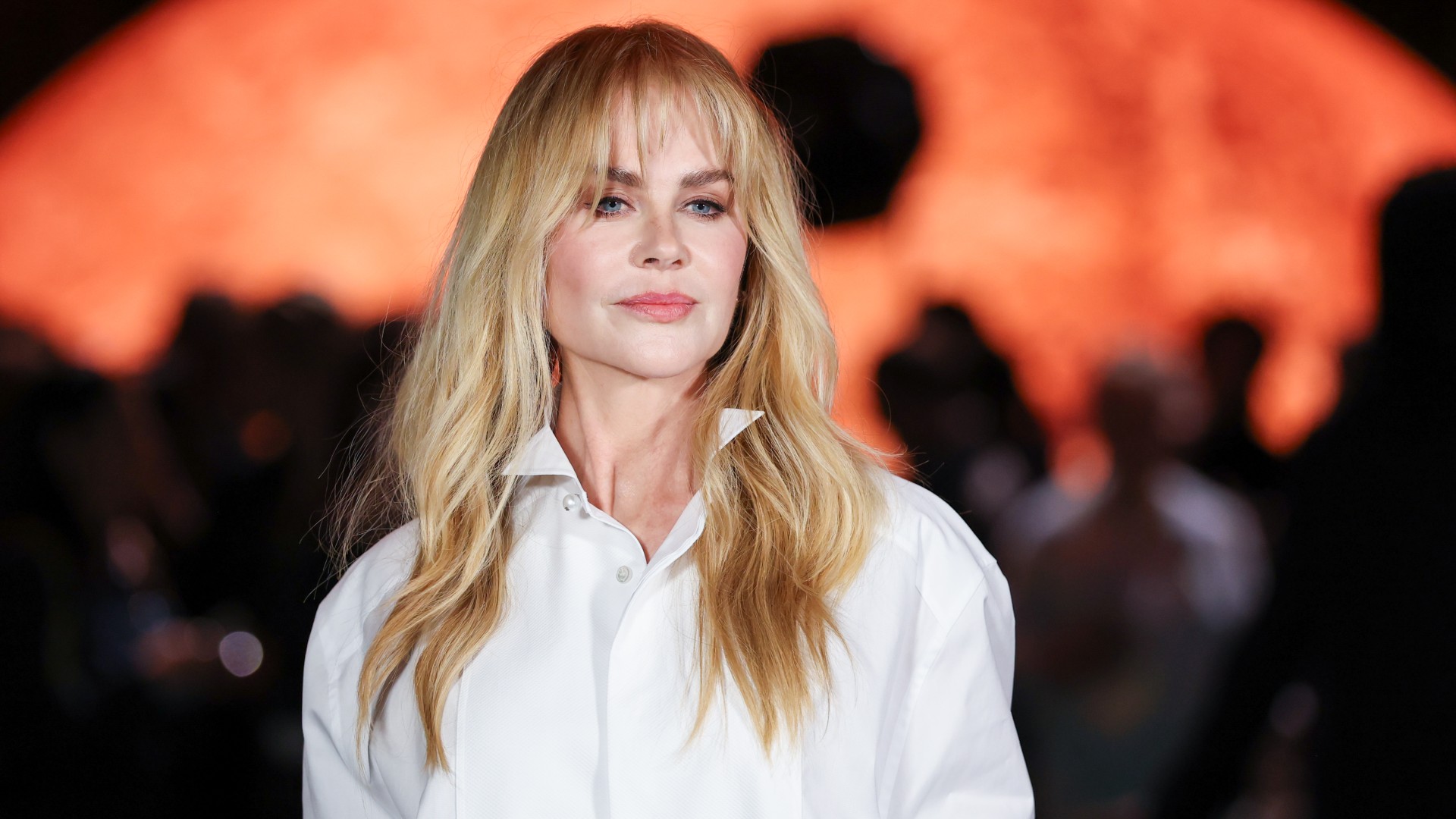 a white woman with long blonde hair and bangs posing for paparazzi at a fashion show