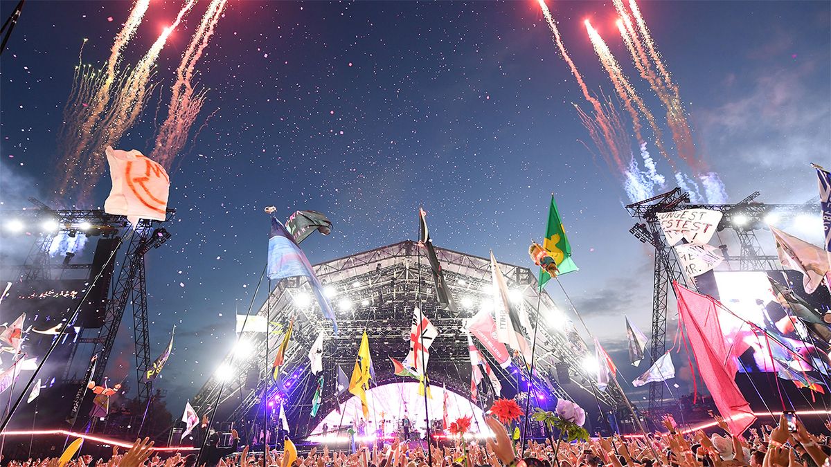 Night time view of Glastonbury Festival stage with crowd and fireworks