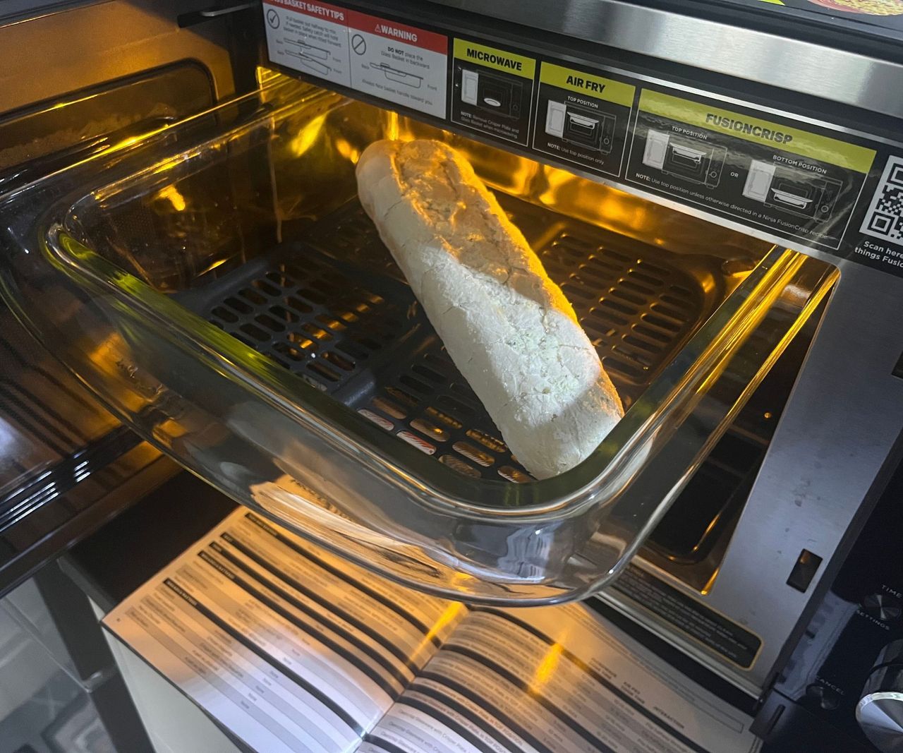 A garlic baguette in a pulled out glass air fryer dish