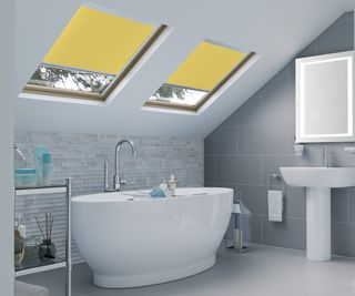 yellow skylight blinds in bathroom with white freestanding bath and grey colour scheme
