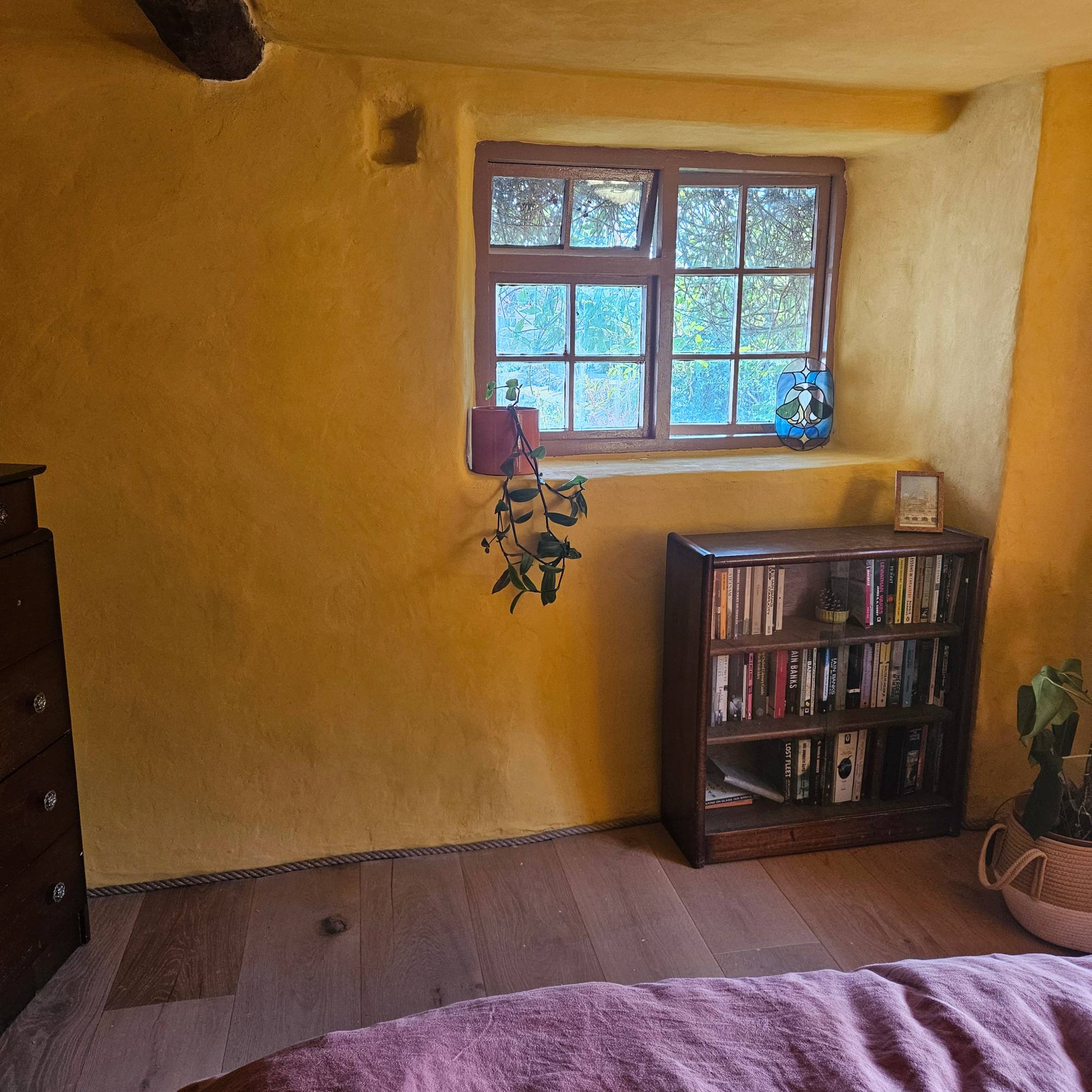 yellow bedroom with brown windows and wooden flooring