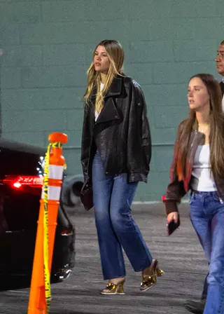 Sofia richie wears saint laurent leather jacket, a white t-shirt, jeans, and gold heels